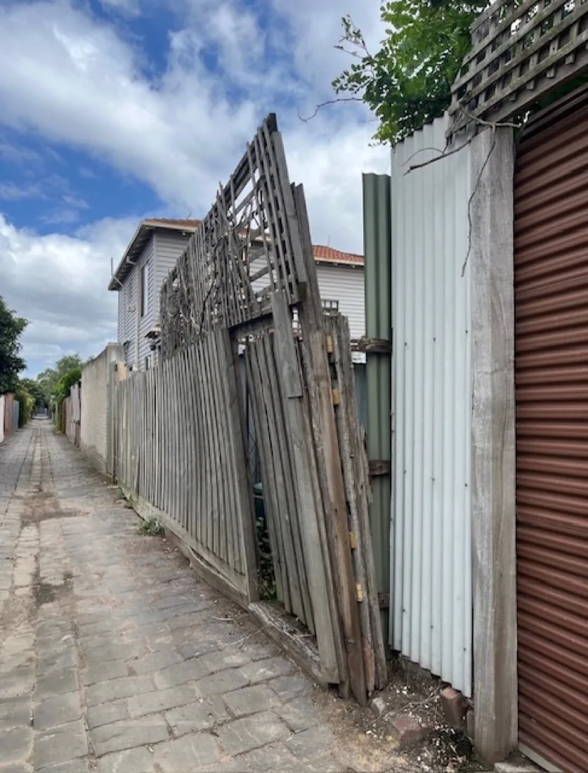 Leaning, broken timber fence before replacement